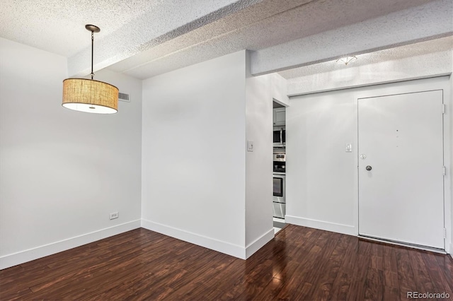 unfurnished room with dark hardwood / wood-style flooring and a textured ceiling