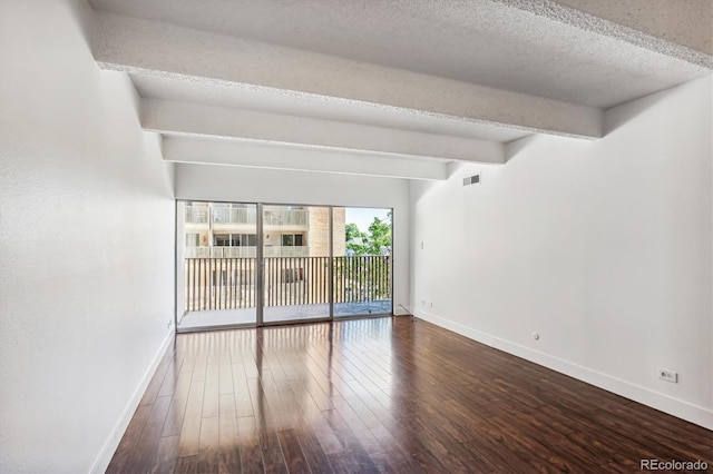 empty room featuring lofted ceiling with beams, wood-type flooring, and a textured ceiling