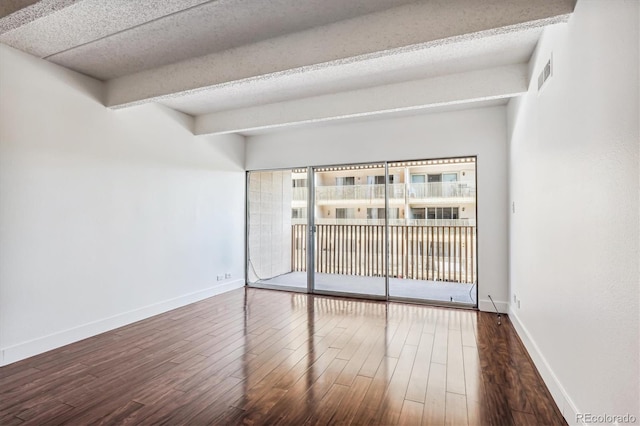 unfurnished room with beam ceiling and dark hardwood / wood-style floors