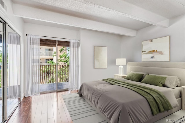 bedroom featuring beamed ceiling, wood-type flooring, a textured ceiling, and access to outside