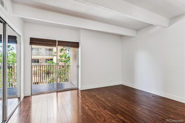 spare room featuring beamed ceiling, hardwood / wood-style floors, and a textured ceiling