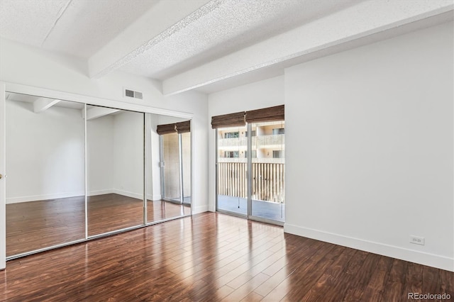 unfurnished bedroom with a closet, beamed ceiling, wood-type flooring, and a textured ceiling