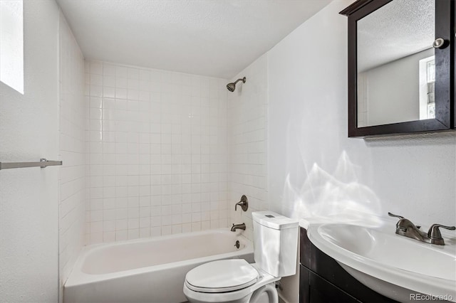 full bathroom with vanity, tiled shower / bath combo, a textured ceiling, and toilet