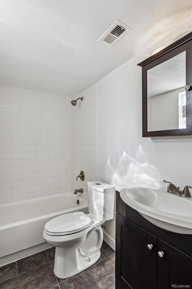 full bathroom with a textured ceiling, vanity, toilet, and tiled shower / bath combo