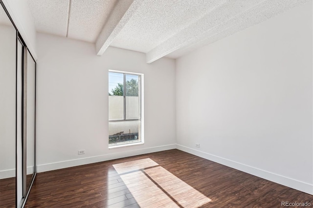 unfurnished bedroom with beam ceiling, dark hardwood / wood-style flooring, a textured ceiling, and a closet