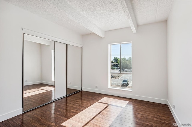 unfurnished bedroom featuring beam ceiling, a textured ceiling, and wood-type flooring