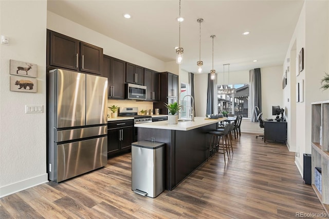 kitchen with light countertops, appliances with stainless steel finishes, dark wood-type flooring, and dark brown cabinets