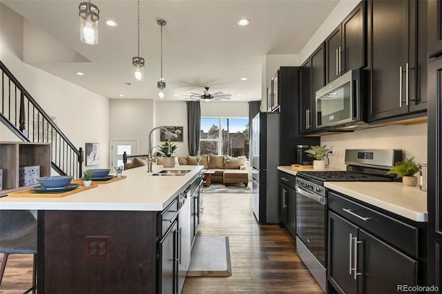 kitchen with a breakfast bar area, appliances with stainless steel finishes, open floor plan, light countertops, and a sink