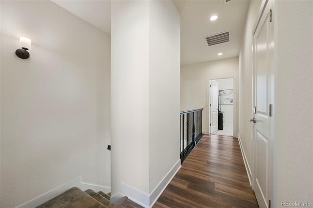 hallway featuring dark wood-style floors, recessed lighting, visible vents, and baseboards