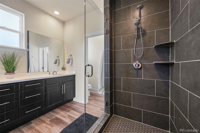 bathroom with recessed lighting, toilet, vanity, a shower stall, and wood finished floors