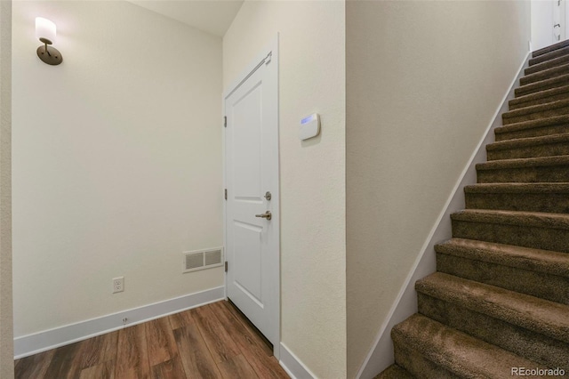 stairway with wood finished floors, visible vents, and baseboards