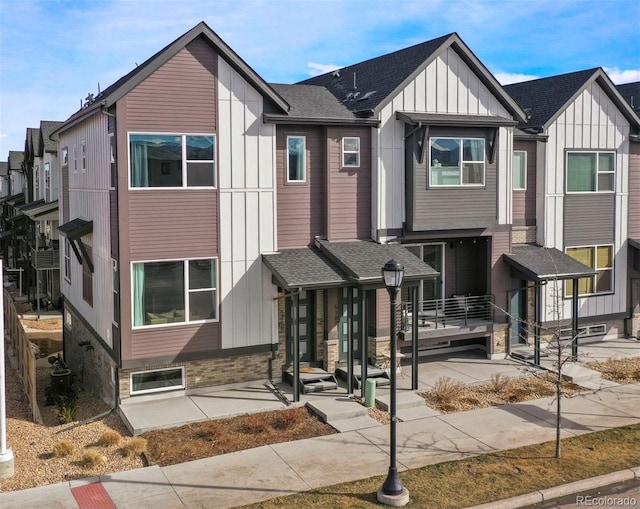 townhome / multi-family property with roof with shingles and board and batten siding