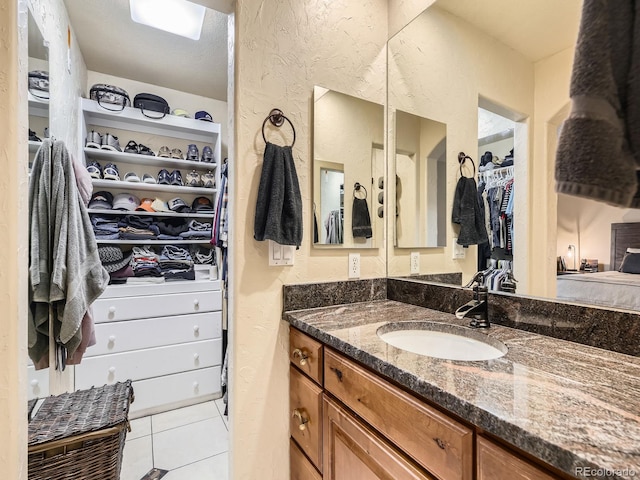 2104 Vineyard Dr, Castle Rock, CO 80104 - bathroom featuring vanity, a spacious closet, tile patterned flooring, and a textured wall
