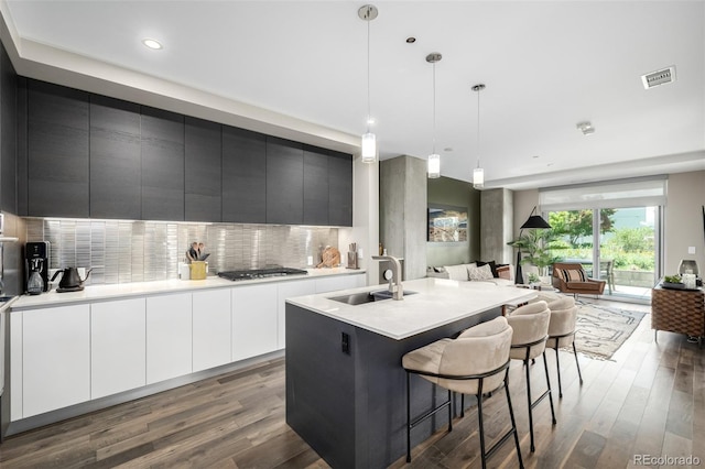 4200 W 17th Ave Unit 212, Denver, CO 80204 - kitchen with wood finished floors, backsplash, modern cabinets, open floor plan, and a kitchen breakfast bar