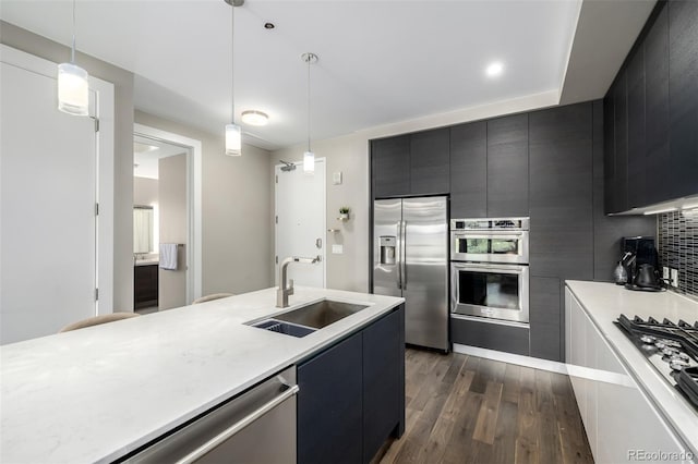 4200 W 17th Ave Unit 212, Denver, CO 80204 - kitchen featuring stainless steel appliances, dark cabinetry, dark wood finished floors, light countertops, and decorative light fixtures