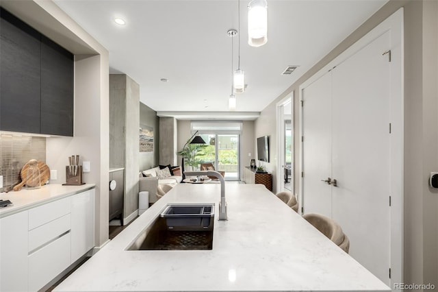 4200 W 17th Ave Unit 212, Denver, CO 80204 - kitchen with modern cabinets, open floor plan, pendant lighting, a breakfast bar area, and backsplash