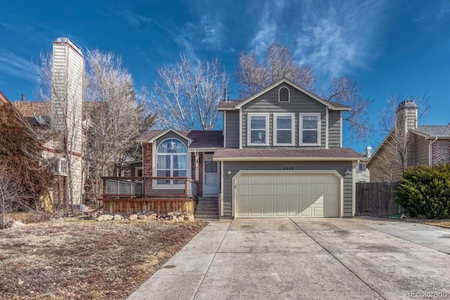 tri-level home featuring a garage, concrete driveway, and fence