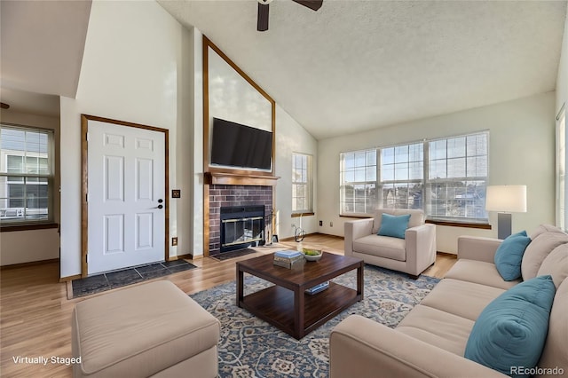 living room featuring ceiling fan, hardwood / wood-style floors, high vaulted ceiling, and a textured ceiling