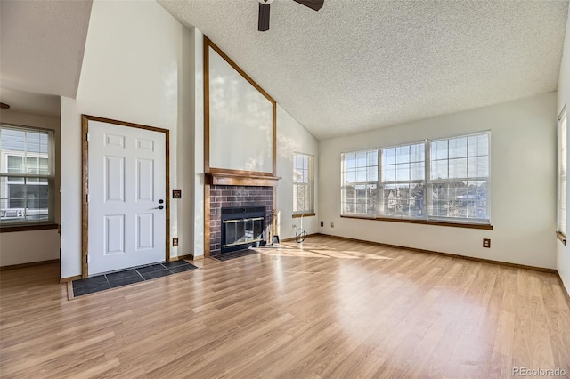 unfurnished living room with a brick fireplace, high vaulted ceiling, ceiling fan, and light hardwood / wood-style floors