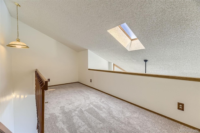 additional living space with a textured ceiling, lofted ceiling with skylight, and carpet