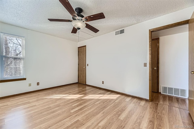 unfurnished room with ceiling fan, light wood-type flooring, and a textured ceiling