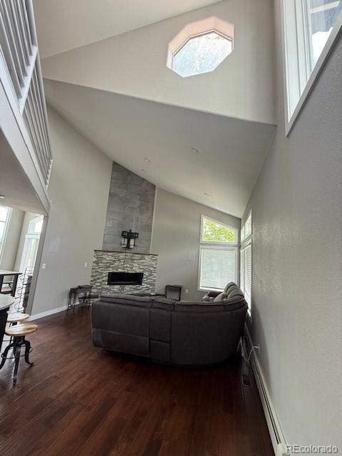 1545 W 148th Ave, Westminster, CO 80023 - living area with high vaulted ceiling, dark wood finished floors, a baseboard radiator, and a stone fireplace