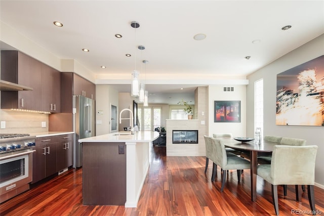 907 E 22nd Ave, Denver, CO 80205 - kitchen with high end appliances, open floor plan, a large fireplace, light countertops, and dark wood-style floors