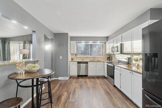 kitchen featuring stainless steel appliances, decorative backsplash, white cabinetry, and sink