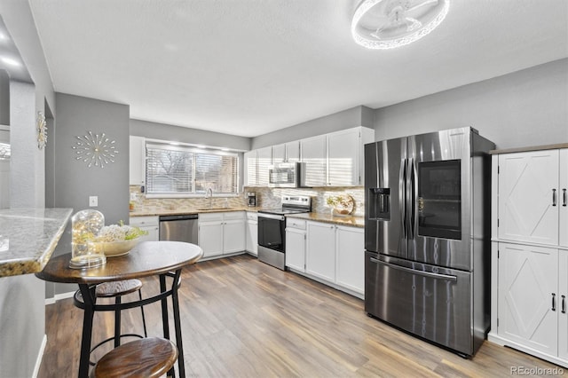 kitchen featuring tasteful backsplash, appliances with stainless steel finishes, sink, and white cabinetry