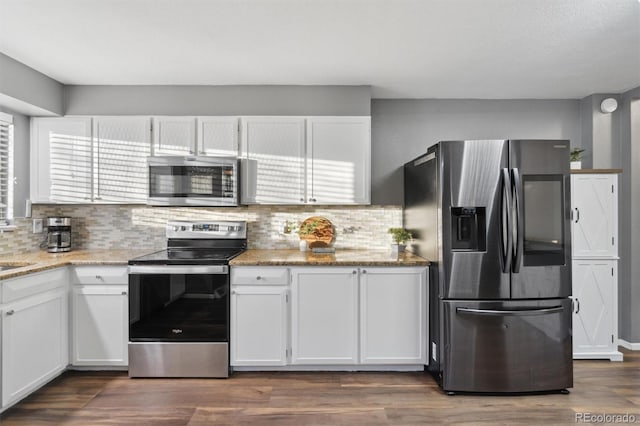 kitchen with white cabinetry, appliances with stainless steel finishes, decorative backsplash, dark hardwood / wood-style flooring, and light stone counters