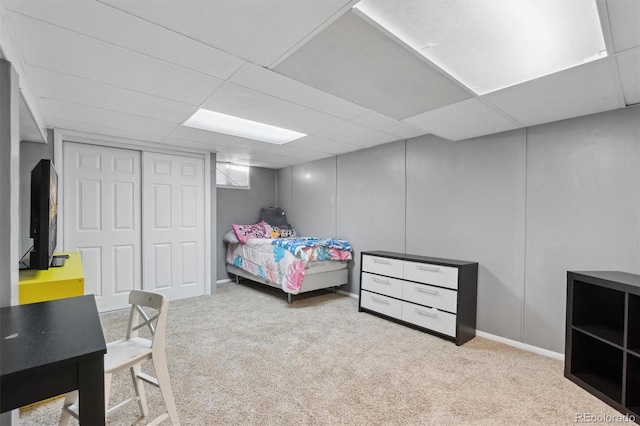 carpeted bedroom featuring a closet and a drop ceiling