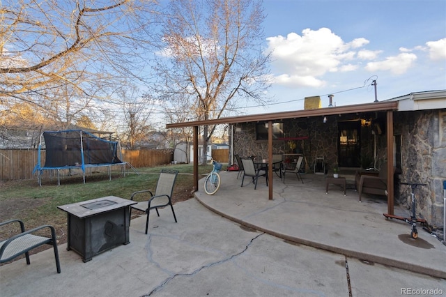 view of patio featuring a trampoline, an outdoor fire pit, and a storage shed