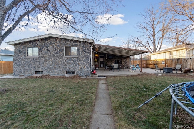 rear view of property featuring a trampoline, a patio area, and a yard