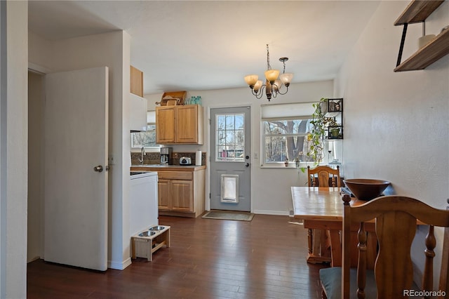 kitchen with a sink, baseboards, dark wood-style floors, an inviting chandelier, and pendant lighting