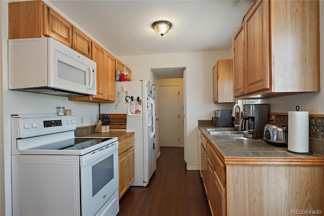 kitchen with dark wood-style floors, dark countertops, white appliances, and a sink