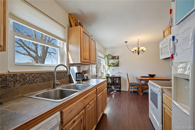 kitchen with white appliances, dark wood-style flooring, a sink, tasteful backsplash, and an inviting chandelier