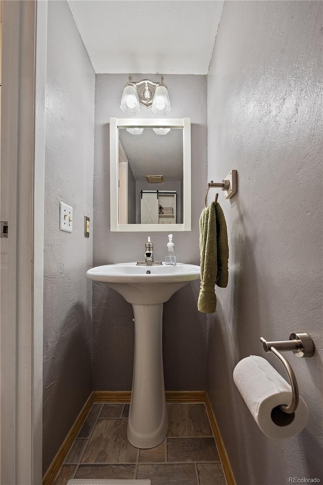 bathroom featuring a textured wall and baseboards