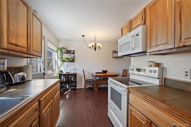 kitchen featuring white appliances, dark wood-type flooring, brown cabinets, dark countertops, and an inviting chandelier