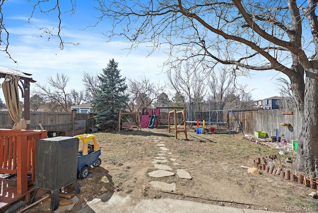 view of yard with a trampoline, a playground, and a fenced backyard