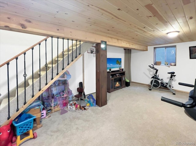 exercise area featuring carpet floors, baseboards, and wood ceiling