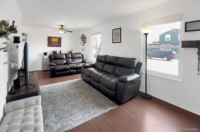 living area featuring baseboards, a ceiling fan, and wood finished floors