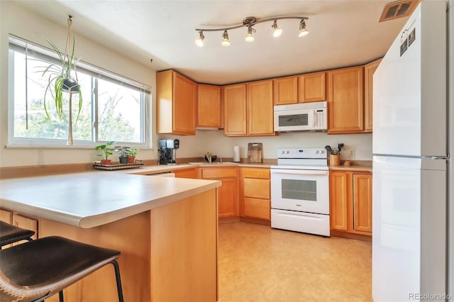 kitchen featuring white appliances, a peninsula, light countertops, and a sink