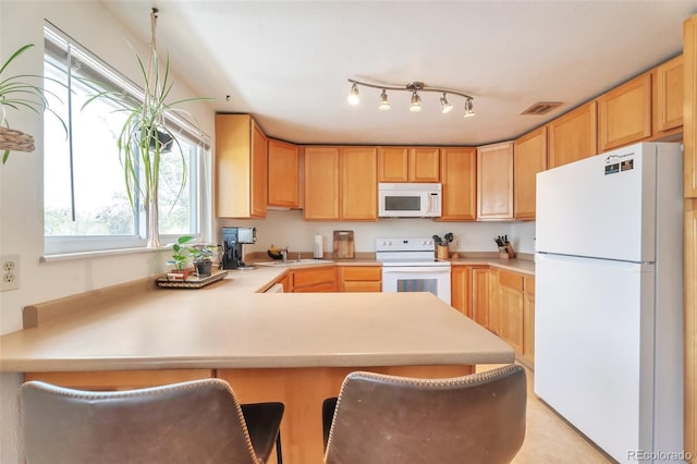 kitchen with white appliances, a peninsula, light countertops, and light brown cabinetry
