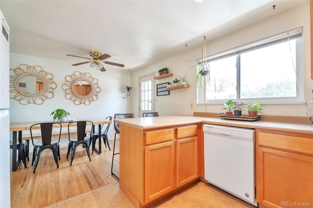 kitchen featuring white dishwasher, a peninsula, a ceiling fan, and light countertops