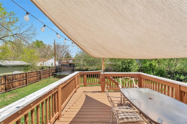 wooden deck with a trampoline and outdoor dining space