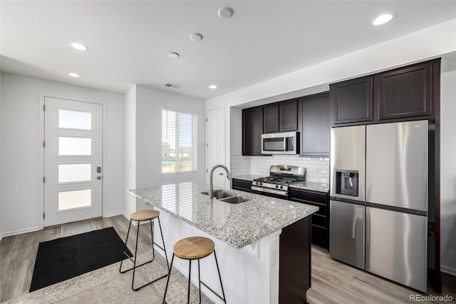18199 E 96th Ave, Commerce City, CO 80022 - kitchen with appliances with stainless steel finishes, a sink, an island with sink, tasteful backsplash, and light stone counters
