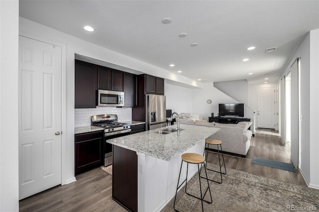 18199 E 96th Ave, Commerce City, CO 80022 - kitchen featuring appliances with stainless steel finishes, a sink, open floor plan, dark wood-style floors, and a breakfast bar