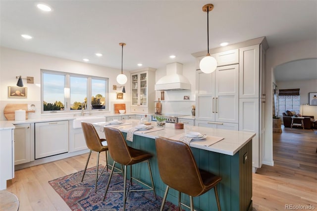 kitchen featuring white cabinetry, light hardwood / wood-style flooring, pendant lighting, and custom range hood