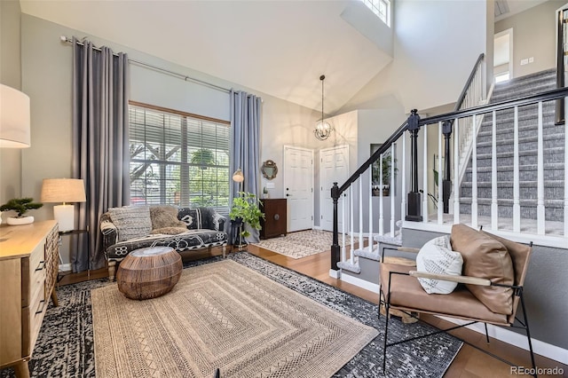 sitting room with stairs, baseboards, wood finished floors, and high vaulted ceiling
