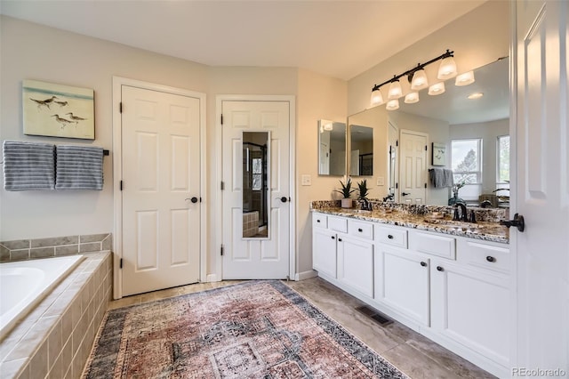 full bath featuring a garden tub, double vanity, and tile patterned floors